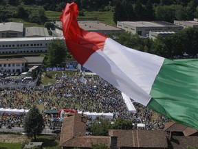 A man waves the Italian flag on a hill during a the traditional League party rally in Pontida, northern Italy, Sunday, July 1, 2018. Italian Interior Minister, and right-wing Northern League Leader Matteo Salvini has vowed that no more humanitarian groups' rescue boats will dock in Italy, where in recent years, private rescue vessels have brought many of the hundreds of thousands of migrants saved from smugglers' boats.