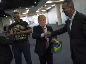 A supporter of Brazil's presidential candidate Jair Bolsonaro, wearing a mask of President Donald Trump, arrives to the National Social Liberal Party convention where Bolsonaro is to accept the nomination in Rio de Janeiro, Brazil, Sunday, July 22, 2018. Far-right congressman Bolsonaro is running in distant second to former President Luiz Inacio Lula da Silva, who is in jail, and promises to clean house ahead of October elections.