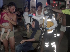 Paramedics help people rescued from a boat that capsized off Cyprus' northern coastline, as he is brought to a hospital in Silifke, near the city of Mersin, southern Turkey, late Wednesday, July 18, 2018. A boat carrying about 150 migrants capsized off the northern coast of Cyprus on Wednesday, with the search continuing and some 105 people rescued so far according to the Turkish coast guard.