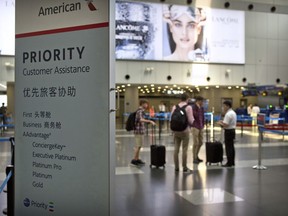 In this July 6, 2018, photo, travelers stand near a signboard at the American Airlines check-in counters at the Beijing Capital International Airport in Beijing. China is applauding U.S. airlines for bending to its demand that they cease referring to Taiwan as its own country on their websites, as American Airlines, Delta and United are among a wave of international carriers to remove references to Taiwan on their websites ahead of a Wednesday, July 25, 2018, deadline set by Chinese authorities.