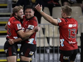Crusaders Braydon Ennor, left, is congratulated by teammate Codie Taylor and Crusaders Jack Goodhue, right, after scoring a try against the Hurricanes during their Super Rugby semifinal in Christchurch, New Zealand, Saturday, July 28, 2018.