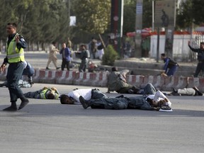 EDS NOTE: GRAPHIC CONTENT -- Afghan security personnel and traffic police lie on the ground after a suicide attack near the Kabul Airport, in Kabul, Afghanistan, Sunday, July 22, 2018. An Afghan official said that an explosion took place shortly after the country's first vice president Gen. Abdul Rashid Dostum landed at the airport.