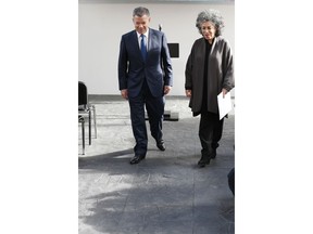 Colombia's President Juan Manuel Santos and artist Doris Salcedo walk over a floor made with melted weapons in Bogota, Colombia, Tuesday, July 31, 2018. The work of art of Salcedo is one of the three monuments being constructed with arms turned over by former rebels of the demobilized Revolutionary Armed Forces of Colombia, FARC, as part of the peace deal signed in 2016.