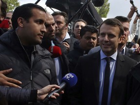 FILE - In this Wednesday April 26, 2017 file photo, Emmanuel Macron, right, is flanked by his bodyguard, Alexandre Benalla, left, outside the Whirlpool home appliance factory, in Amiens, northern France. Investigators have detained for questioning on Friday, July 20, 2018 one of President Emmanuel Macron's top security aides caught on camera beating a protester in May, a turn of events now evolving into a major political crisis for the president. The presidential Elysee Palace said it is taking steps to fire Alexandre Benalla, who was identified earlier this week by the newspaper Le Monde for beating a young protester during May Day protests while wearing a police helmet