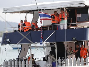 Tourists look out from a tour boat at the Chalong pier in Phuket, Thailand, Sunday, July 8, 2018. Thai authorities have begun operations to salvage a tour boat that sank in a storm off the southern resort island of Phuket, killing 41 people, as they search for another 14 missing tourists.