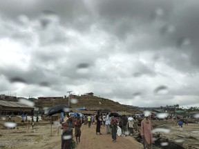 In this June 26, 2018, photo, Rohingya refugees walk in the rain though Jamtoli refugee camp in Bangladesh. The monsoon season has arrived in Bangladesh, bringing fresh dangers to the 900,000 Rohingya refugees who live in ramshackle huts on unstable hills.