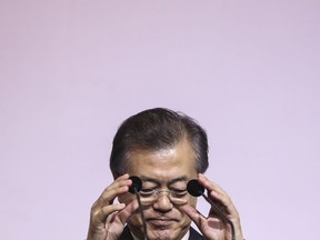 South Korea's President Moon Jae-in adjusts the microphones prior to delivering the 42nd Singapore Lecture organized by the Institute of South East Asian Studies (ISEAS) in Singapore, Friday, July 13, 2018.