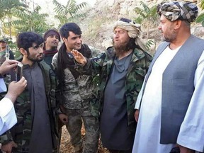 A foreign ISIL fighter, second right, speaks to a journalist after he surrendered to government security forces in the Darzab district of Jawzjan province, north of Kabul, Afghanistan, Wednesday, Aug. 1, 2018.