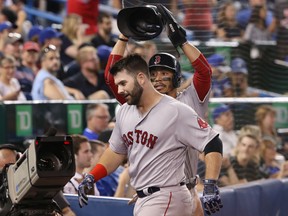 Mitch Moreland of the Boston Red Sox is congratulated by teammate Mookie Betts after hitting a three-run homer in the 10th inning during their game against the Blue Jays at Rogers Centre in Toronto on Tuesday night.