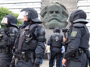 People patrol next to a sculpture of Karl Marx on August 27, 2018 in Chemnitz, eastern Germany, following the death of a 35-year-old German national after what police called a "dispute between several people of different nationalities."
