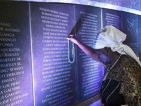 80-year old Margaret Achieng places a rosary on her daughters name Doreen Aluoch at plague with the names of victims of the August 7, 1998 US embassy bombing at the Kenya's capital Nairobi during the 20th commemoration at the memorial park, Nairobi, Kenya, Tuesday, Aug. 7, 2018.