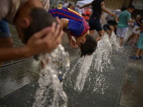 People cool off with water from a fountain during a hot summer day, in the basque city of Vitoria, northern Spain, Saturday, Aug. 4, 2018. Hot air from Africa is bringing a heat wave to Europe, prompting health warnings about Sahara Desert dust and exceptionally high temperatures that could peak at 47 degrees Celsius (117 Fahrenheit) in Spain and Portugal.