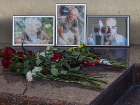 A picture taken on August 1, 2018 shows flowers left in front of the photographs of Russian journalists (L-R) Alexander Rastorguyev, Kirill Radchenko and Orkhan Dzhemal, who were recently killed in the Central African Republic, outside the Central House of Journalists.