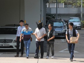This handout photograph from Apple Daily taken on September 11, 2017 shows Malaysian national Khaw Kim-sun (C), who is accused of murdering his wife and daughter, being escorted by police at Ma On Shan Police Station in Hong Kong.