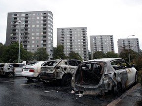 Burned cars parked at Frolunda Square in Gothenburg, Tuesday,  Aug. 14, 2018. Masked youth torched dozens of cars overnight in Sweden and threw rocks at police, prompting an angry response from the prime minister, who on Tuesday spoke of an "extremely organized" night of vandalism.