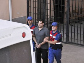 Turkish paramilitary police officers escort Greek soldier Dimitros Kouklatzis following a court appearance in Edirne, Turkey, Tuesday, Aug. 14, 2018.  Turkey on Tuesday released from prison two Greek soldiers held since March 1 for allegedly illegally crossing the border between the two countries, in a move hailed by Greece's prime minister as "an act of justice."(DHA via AP )