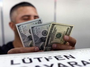 An official checks US dollar banknotes before changing them for Turkish lira currency inside a currency exchange office in Ankara, Turkey, Friday, Aug. 17, 2018. Turkey and the United States exchanged new threats of sanctions Friday, keeping alive a diplomatic and financial crisis.