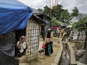 In this Thursday, Aug. 23, 2018 photo, a Rohingya refugee woman sits at the door of her makeshift bamboo and tarp shelter at Kutupalong refugee camp, Bangladesh. First built more than 20 years ago by earlier, smaller waves of Rohingya refugees, the camps in Cox's Bazar district exploded in size last year when Myanmar's army launched its attacks around Aug. 25, and hundreds of thousands of Rohingya began flooding across the border.