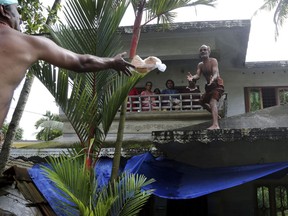 A volunteer throws a pack of bread towards a family stranded in a flooded area in Chengannur in the southern state of Kerala, India, Sunday, Aug.19, 2018. Some 800,000 people have been displaced and over 350 have died in the worst flooding in a century.