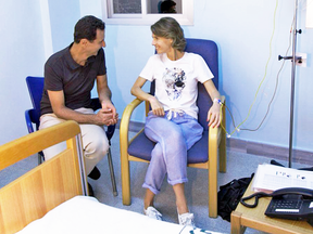 This photo posted Aug 8, 2018, shows Syrian President Bashar Assad sits next to his wife Asma Assad, who has an IV in her left arm in what appears to be a hospital room in Syria.