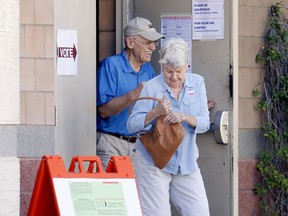 A couple exit their polling station after voting, Tuesday, Aug. 28, 2018, in Phoenix. Equipment issues and a shortage of workers may keep Arizona polls open two hours later today.
