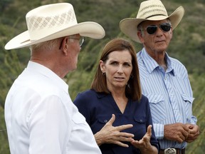 In this Wednesday, Aug. 22, 2018, U.S. Senatorial candidate U.S. Rep. Martha McSally, R-Ariz., stands at the international border with Mexico, with ranchers Jim Chilton, left, and Tom Kay, right, south of Arivaca, Ariz. In her bid to become the Republican Senate nominee, McSally has tacked hard right after initially keeping her distance from President Donald Trump.