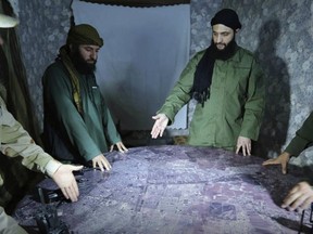 FILE -- This undated file photo released by a militant group in 2016, shows Abu Mohammed al-Golani of the militant Levant Liberation Committee and the leader of Syria's al-Qaida affiliate, second right, discussing battlefield details with field commanders over a map, in Aleppo, Syria. Al-Golani vowed to fight on in Idlib province, the country's last major rebel stronghold, in the face of a possible government offensive in a video posted online to mark the Muslim feast of Eid al-Adha, shortly before midnight Tuesday, Aug. 22, 2018. (Militant UGC via AP, File)