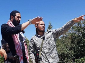 This undated photo released by the militant group Levant Liberation Committee on Tuesday, Aug. 21, 2018, shows Abu Mohammed al-Golani of the militant Levant Liberation Committee and the leader of Syria's al-Qaida affiliate, left, talking with a fighter, in the countryside of Latakia, Syria. Al-Golani vowed to fight on in Idlib province, the country's last major rebel stronghold, in the face of a possible government offensive in a video posted online to mark the Muslim feast of Eid al-Adha, shortly before midnight Tuesday, Aug. 22, 2018. (Militant UGC via AP)