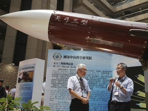 FILE - In this Aug. 13, 2015, file photo, two men speak under the Taiwan-made "Tien-Kung III" surface to air missile during the 2015 Taipei Aerospace and Defense Technology Exhibition in Taipei, Taiwan. Taiwan is responding to China's defense buildup by developing missiles and interceptors of its own that could reduce Beijing's military advantage over the island, defense experts say.