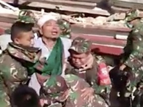 In this image made from video released by the Indonesian military, a man is carried by Indonesian military after they rescued him from a collapsed mosque in the powerful earthquake, Tuesday, Aug. 7, 2018, on the island Lombok, Indonesia. Soldiers were able to rescue the man while thousands of homeless locals waited for aid Tuesday and stranded tourists camped at beaches and in the lobbies of damaged hotels.