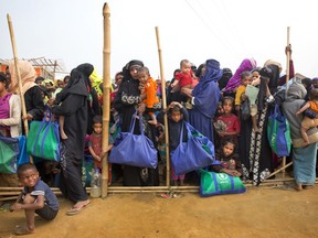 FILE - In this Jan. 15, 2018, file photo, Rohingya Muslim women with their children stand in a queue outside a food distribution center at Balukhali refugee camp 50 kilometers (32 miles) from, Cox's Bazar, Bangladesh. The human rights group Human Rights Watch is calling on Bangladesh's government to abandon controversial plans to relocate Rohingya refugees to a small, uninhabited island said to be at severe risk of serious flooding.