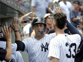 Giancarlo Stanton, centre, is congratulated in the Yankees dugout after hitting a solo home run off Toronto Blue Jays starting pitcher Sean Reid-Foley during the fourth inning of their game on Saturday in New York.