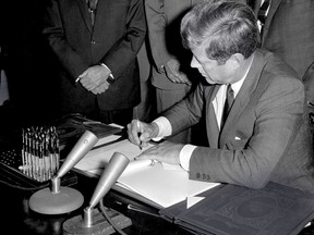 FILE - In this Oct. 7, 1963, file photo, President John F. Kennedy signs the Limited Test Ban Treaty during a ratification ceremony in the White House Treaty Room in Washington. Beginning Friday, Aug. 3, 2018, Eldred's auction gallery in East Dennis, Mass., on Cape Cod, is auctioning items associated with the late president, including pens that Kennedy used to sign the treaty. (AP Photo/File)