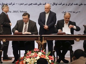 FILE - In this July 3, 2017 file photo, Chairman and CEO of France's Total SA Patrick Pouyanne, seated second left, managing director of Iran's Petropars Hamid Akbari, left, CEO of National Iranian Oil Company Ali Kardor, second right, and President of China's CNPC International Lv Gongxun sing the documents of a contract to develop an Iranian gas field, as Iranian Oil Minister Bijan Zanganeh, standing at center, and Chinese ambassador to Tehran Pang Sen look on, in Tehran, Iran. Iran's oil minister said Monday, Aug. 20, 2018, that France's oil giant Total SA has pulled out of Iran after cancelling its $5 billion, 20-year agreement to develop the country's massive South Pars offshore natural gas field over renewed U.S. sanctions.