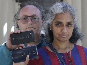 In this July 25, 2018 photo, Kalyanaraman Shankari, right, and her husband Thomas Raffill hold their phones while posing for photos in Mountain View, Calif. An Associated Press investigation shows that using Google services on Android devices and iPhones allows the search giant to record your whereabouts as you go about your day. Shankari, a graduate researcher at UC Berkeley who connects commuting patterns with urban planners, noticed that her Android phone prompted her to rate a shopping trip to Kohl's. That happened even though she had turned off Google's "location history" setting, which according to the company should prevent it from remembering where a user has been.