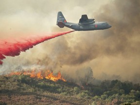 A U.S. Air Force plane drops fire retardant on a burning hillside in the Ranch Fire in Clearlake Oaks, Calif., Sunday, Aug. 5, 2018.