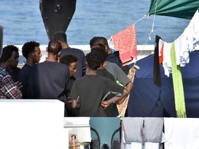 Migrants aboard the Italian Coast Guard ship Diciotti talk as they await decisions in the port of Catania, Italy, Friday, Aug. 24 2018. An Italian lawmaker says rescued migrants stuck aboard an Italian coast guard ship are starting a hunger strike. Rescued on Aug. 16 in the Mediterranean Sea, 150 migrants are still on the ship after minors and the sick were allowed off in recent days.