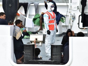 Migrants wait to disembark from Italian Coast Guard ship Diciotti in the port of Catania, Italy, Thursday, Aug. 23, 2018. A delegation from Italy's guarantor of personal rights office has boarded a coast guard ship in a Sicilian port with 150 African migrants stuck aboard for days, after the Italian interior minister vowed none will set foot on Italian soil.