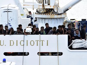 Migrants aboard the Italian Coast Guard ship Diciotti gather on the deck as they await decisions in the port of Catania, Italy, Friday, Aug. 24 2018. An Italian lawmaker says rescued migrants stuck aboard an Italian coast guard ship are starting a hunger strike. Rescued on Aug. 16 in the Mediterranean Sea, 150 migrants are still on the ship after minors and the sick were allowed off in recent days.