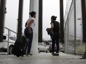 FILE - In this June 20, 2018, file photo, sisters from Guatemala seeking asylum, cross a bridge to a port of entry in to the United States from Matamoros, Mexico, in Brownsville, Texas. The American Civil Liberties Union is suing the U.S. government over its effort to restrict immigrants from seeking asylum on the grounds that they would suffer domestic or gang violence in their countries of origin. The ACLU's lawsuit asks a judge to invalidate Attorney General Jeff Sessions' June 11 memo that tightened the restrictions on what kind of cases qualify for asylum.