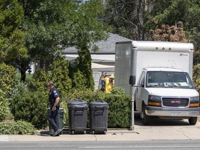 An Aurora, Colo., Police Department officer walks down the sidewalk as another officer in protective gear loads a box truck in front of the home of a man who was shot and killed by police Tuesday, July 31, 2018, in Aurora, Colo. The homeowner was shot after he killed an intruder at his home early Monday as police responded to calls for help at the home.