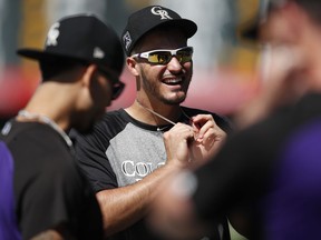 Colorado Rockies third baseman Nolan Arenado, center, jokes with teammates as they warm up before a baseball game against the Los Angeles Dodgers, Saturday, Aug. 11, 2018, in Denver.