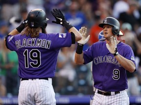 Colorado Rockies' Charlie Blackmon, left, congratulates DJ LeMahieu, who crosses home plate after hitting a two-run home run off Los Angeles Dodgers starting pitcher Kenta Maeda during the first inning of a baseball game Friday, Aug. 10, 2018, in Denver.