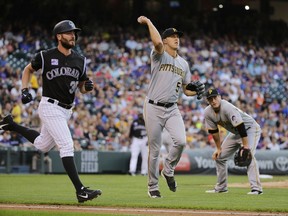 Pittsburgh Pirates starting pitcher Jameson Taillon throws out Colorado Rockies' Chad Bettis, left, at first base during the third inning of a baseball game Tuesday, Aug. 7, 2018, in Denver.