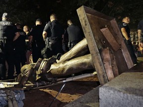 Police stand guard after the confederate statue known as Silent Sam was toppled by protesters on campus at the University of North Carolina in Chapel Hill, N.C., Monday, Aug. 20, 2018.