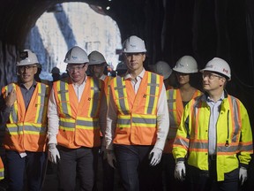 Prime Minister Justin Trudeau, second right, and Minister of Infrastructure and Communities Francois-Philippe Champagne walks through a tunnel as he visits a site for a STM maintenance garage in Montreal on August 9, 2018.