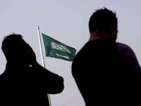 People pray at an open air makeshift mosque in front of a giant Saudi Flag in Jiddah, Saudi Arabia, Wednesday, June 21, 2017. A health care group that represents the majority of university hospitals says losing Saudi Arabian medical residents could cause delays in the delivery of care but won't impact quality.