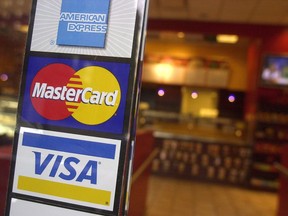 Signs for American Express, MasterCard and Visa credit cards are shown at the entrance to a New York coffee shop on April 22, 2005. The federal government will announce today that major credit card companies have agreed to lower the fees they charge the country's businesses,