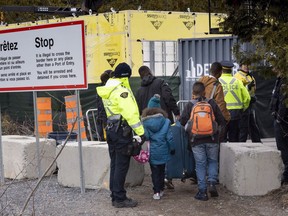 A family claiming to be from Colombia is arrested by RCMP officers as they cross the border into Canada near Champlain, N.Y., on April 18, 2018.