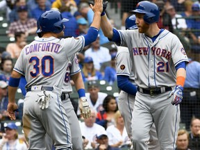 New York Mets' Todd Frazier (21) high-fives Michael Conforto (30) after they scored on Frazier's grand slam in the first inning of a baseball game against the Chicago Cubs, Wednesday, Aug. 29, 2018, in Chicago.